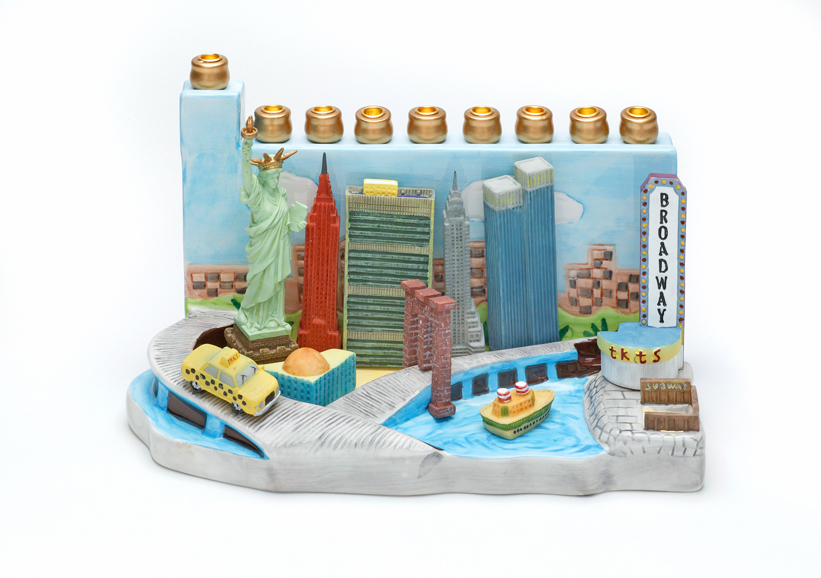 Shepsil Scheinberg, Chanukka-Lampe: “New York City Skyline Memorial Menorah”, China 2000 – 2004, Keramik, bemalt, gebrannt; Kunstharz, gegossen, bemalt; Metall; Karton, beschichtet, bedruckt, 16,5 x 28 x 15 cm;